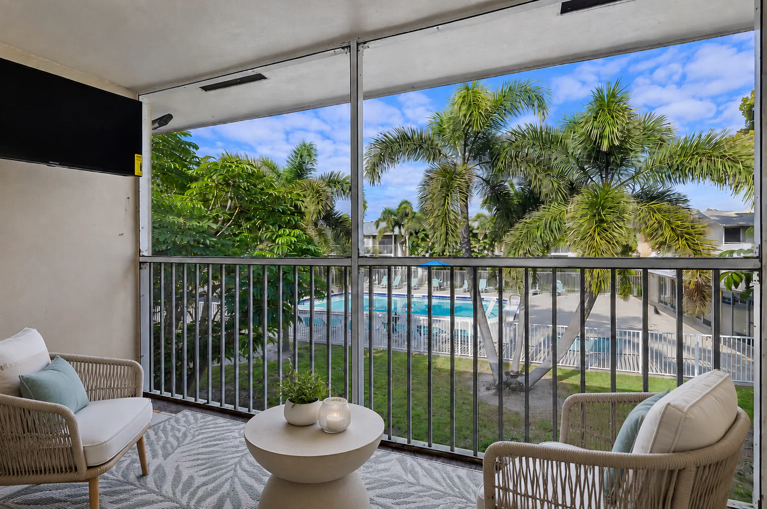 Screened balcony overlooking palm trees and the community pool